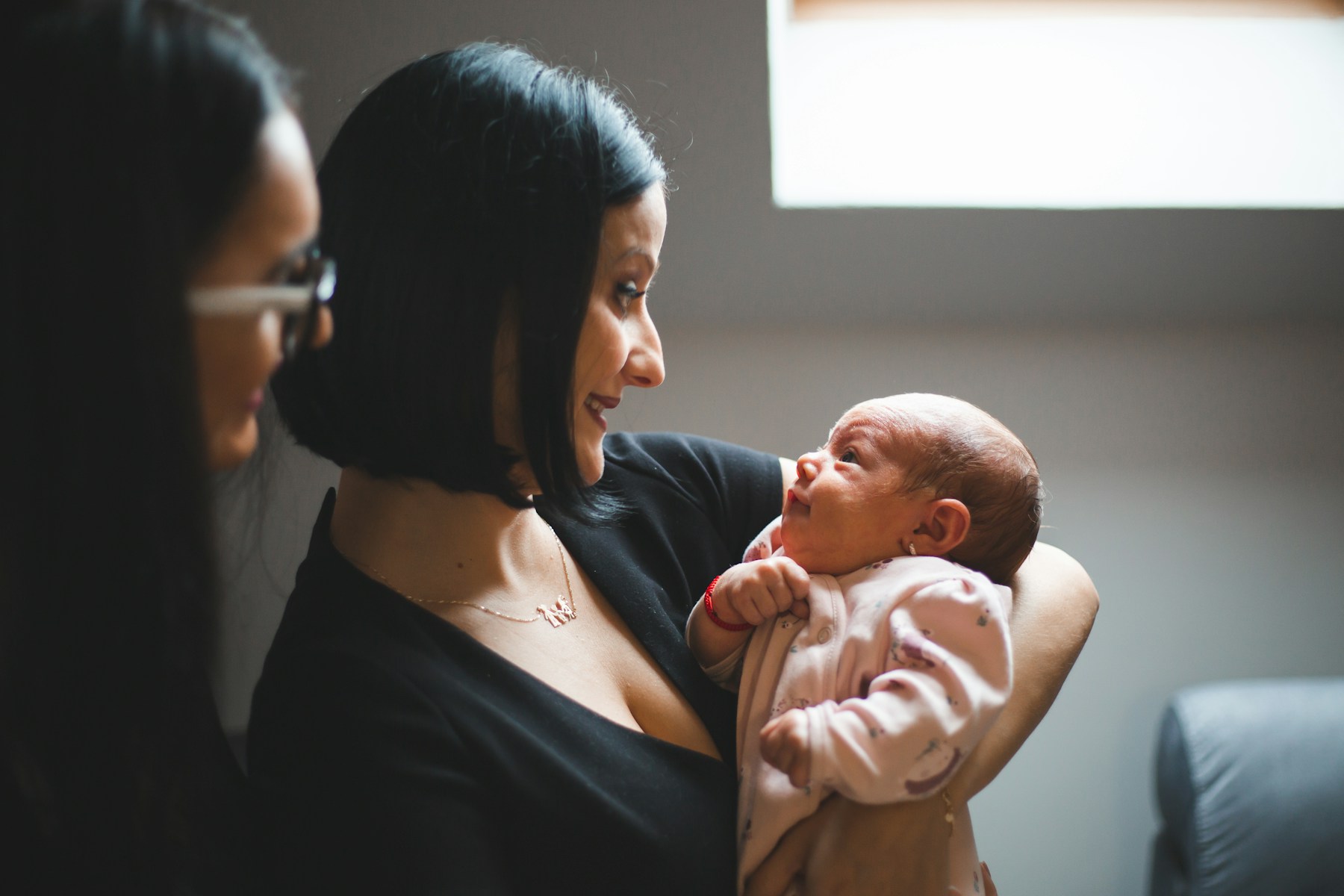 Une maman tient doucement son nouveau-né près d’une fenêtre